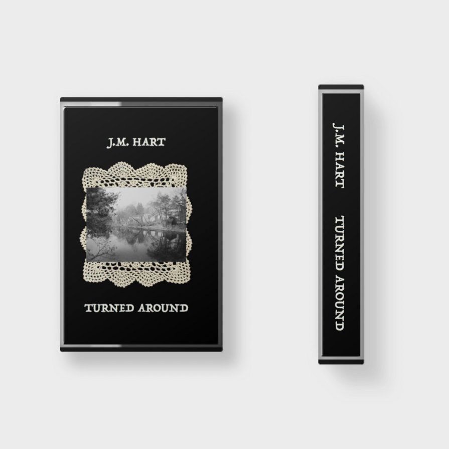 This is kind of what a pair of my new tapes might look like if on lay on its back and another stood on edge so you could see their front and spine, respectively.
The front of the tape is black with a black and white photo of a river sitting in a doily. It has my name, “J.M. Hart” and the album name, “Turned Around” printed on it.  The spine has both names on it as well.
