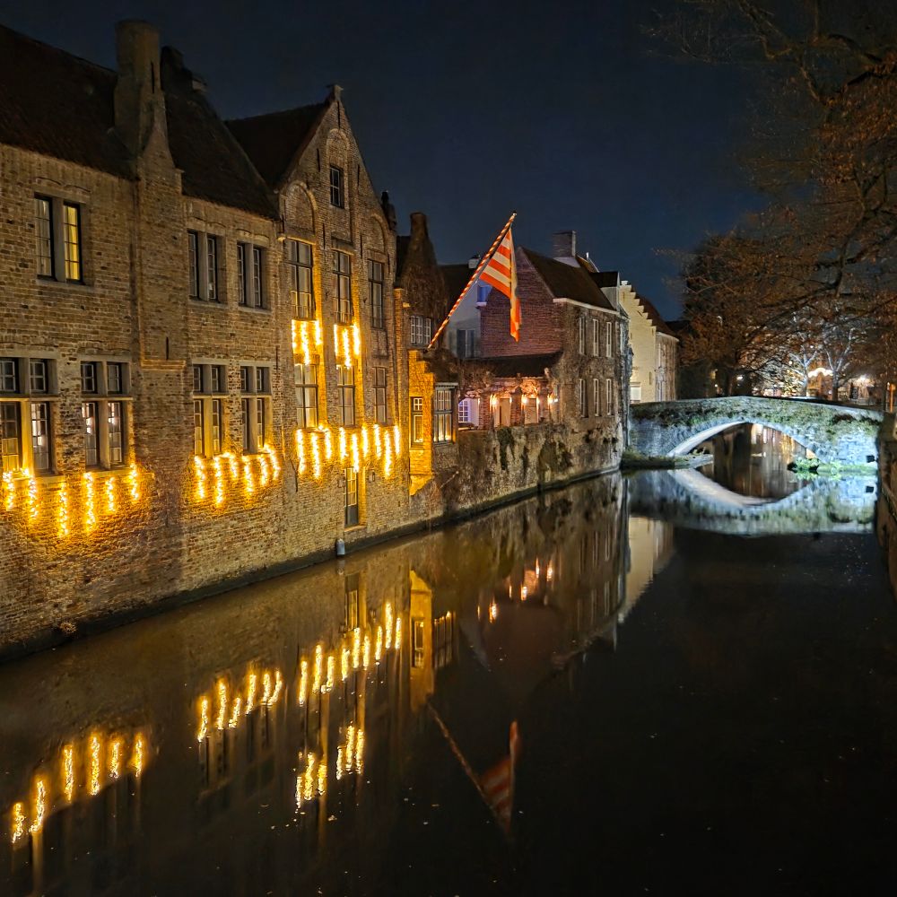Floodlit buildings by the canal at night. There's a floodlit bridge to the right.