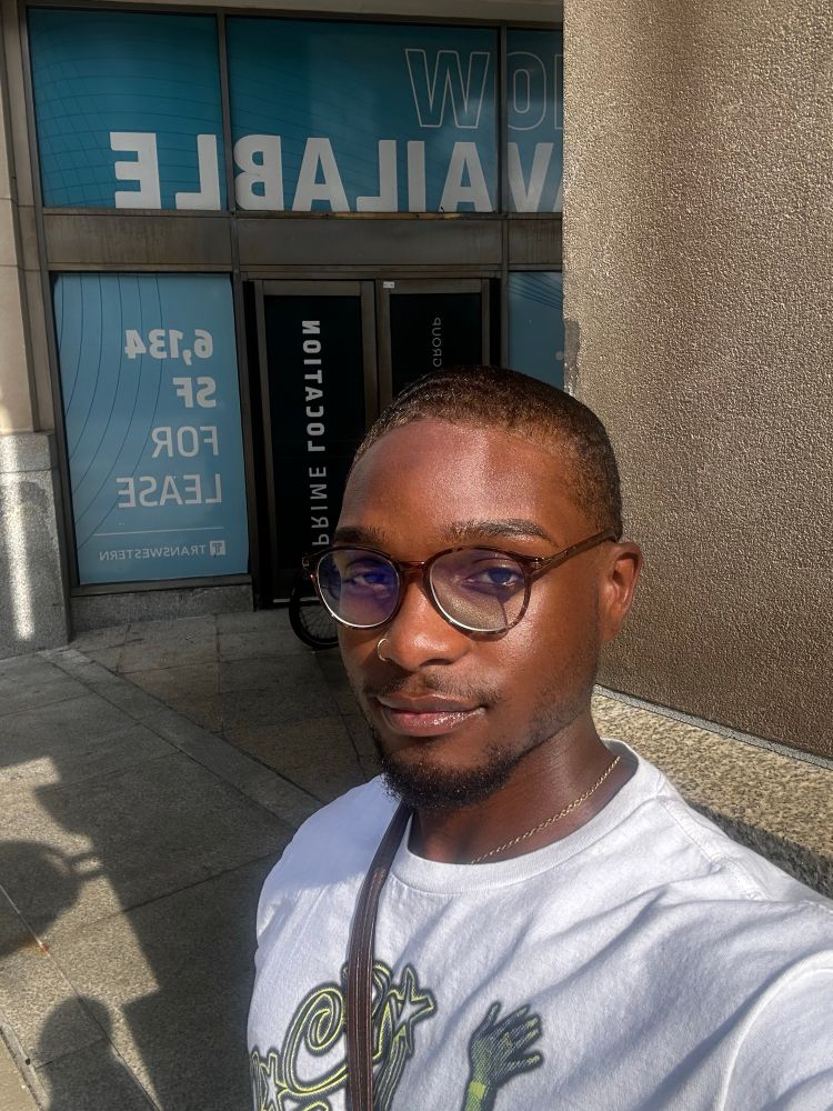 Local gay nigga, taking a selfie, wearing circular glasses, an ice spice t-shirt and a cross body. 