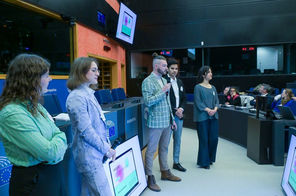 Cinq étudiants et étudiantes en pleine présentation devant le Parlement Européen.