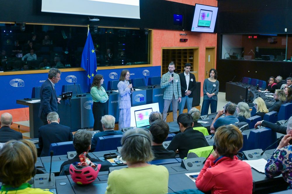 Cinq étudiants et étudiantes en pleine présentation devant le Parlement Européen.
