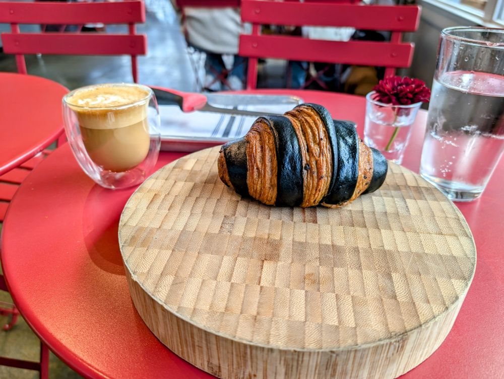 Black and brown bi-color croissant and a cappuccino 