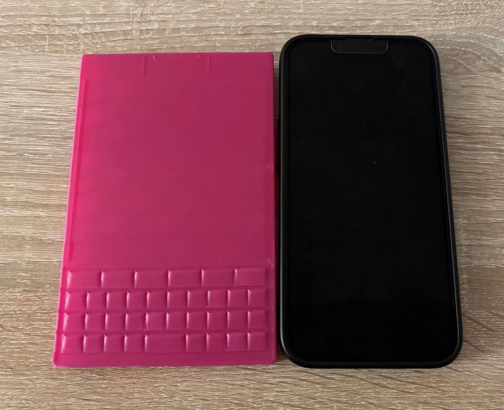 3D tisk makety Titan 2 v růžové barvě a vedle iPhone. 