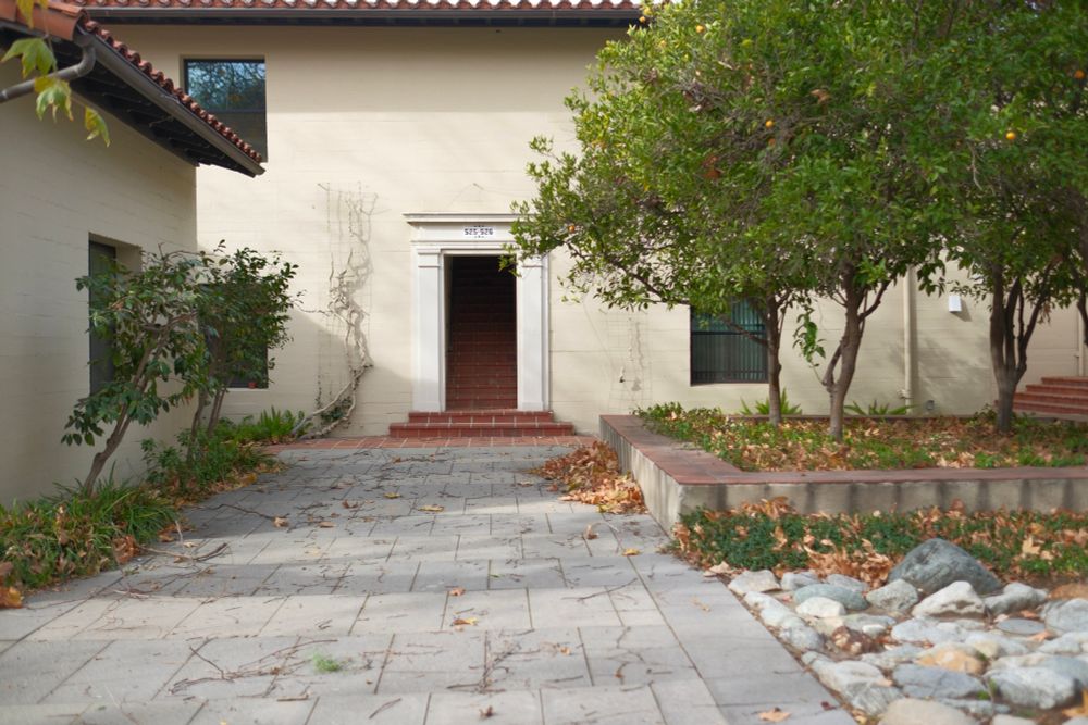 A brick walkway leading to a Spanish style architectural doorway of a college
