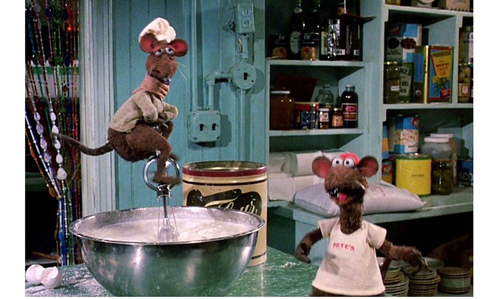 scene in Muppets take Manhattan showing Rizzo the rat and rat friend baking in the kitchen of Pete’s Diner. In this scene one rat is shown riding in a manual egg beater like a unicycle.
