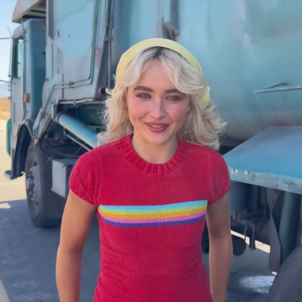 Sabrina Carpenter in a maroon top with a rainbow stripe across the chest.