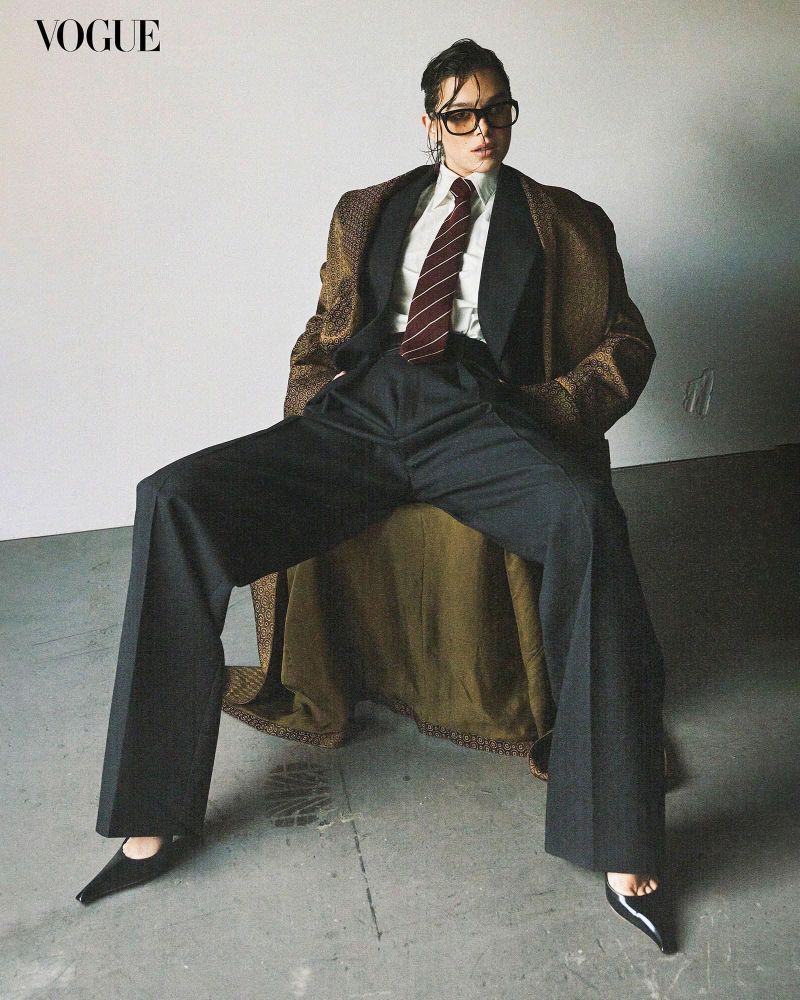 Hailee Steinfeld from a Vogue photoshoot, wearing a suit and long brown overcoat, resembling the outfit worn by the 10th Doctor.