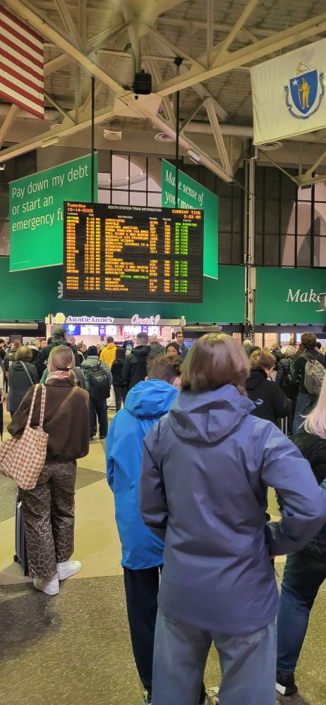 Amtrak south station, I believe in Boston. People on the bottom and a board displaying arrivals and departures on the top 