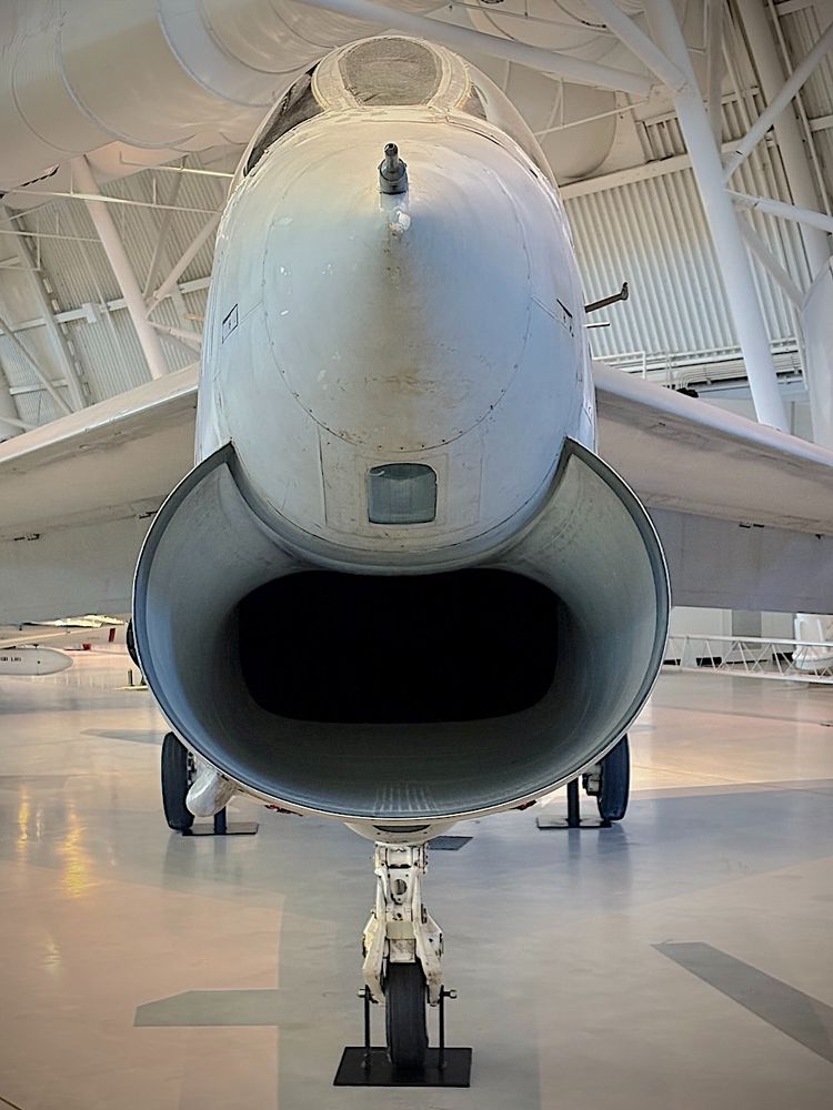 Head-on photo of the jet intake on a parked navy-gray aircraft.