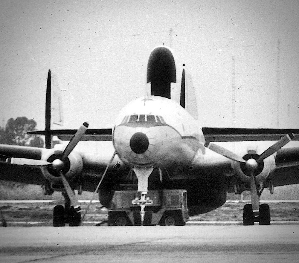 Black and white head-on photo of parked EC-121, generator situated behind nose gear. 