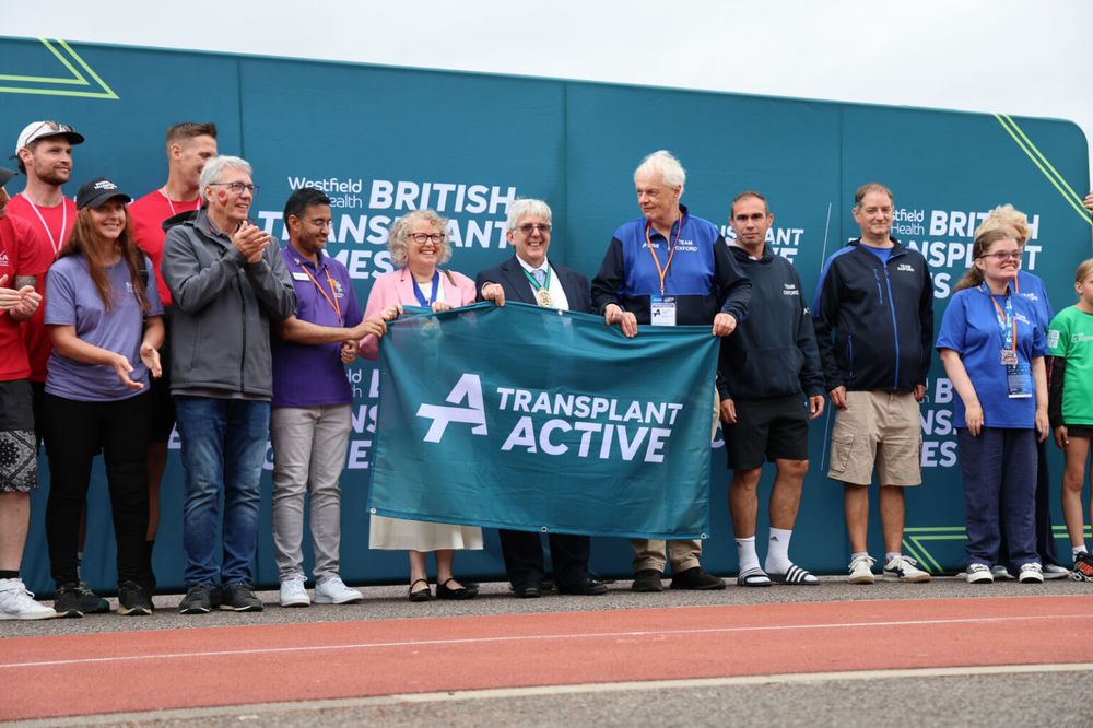Deputy Lord Mayor of Sheffield and other officials lined up in front of a British Transplant Games backdrop, holding a blue Transplant Active flag. 