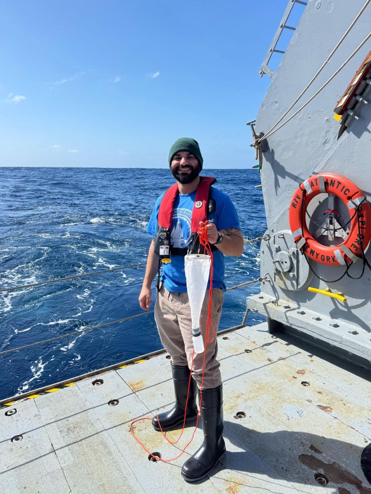 Dr. Loay Jabre stands on the deck of the R/V Atlantic Explorer holding a plankton net that he used to collect samples for the Planktoscope on the 2025 C-CoMP March Cruise. Photo provided by Loay Jabre.