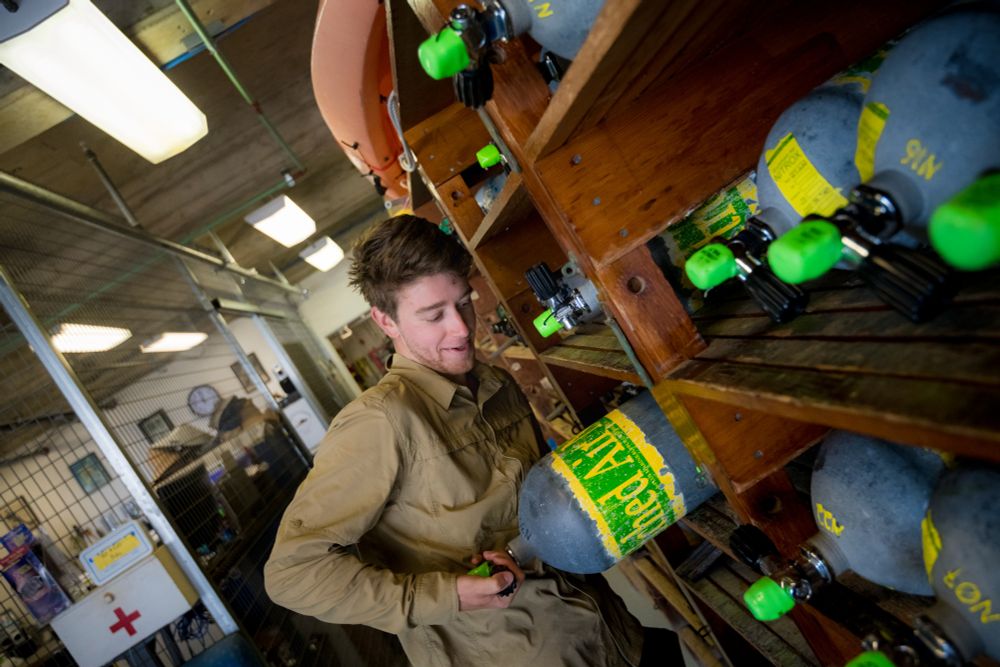 Wiley pulls a scuba cylinder from a rack in the dive locker. Photo by Erik Jepsen. 