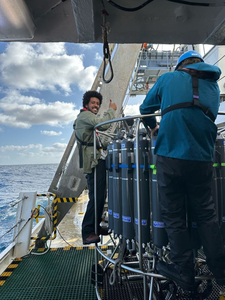 Ben stands on the side of the CTD rosette on the deck of the RV Atlantic Explorer during the C-CoMP March 2025 cruise. Photo by McKenzie Powers. 