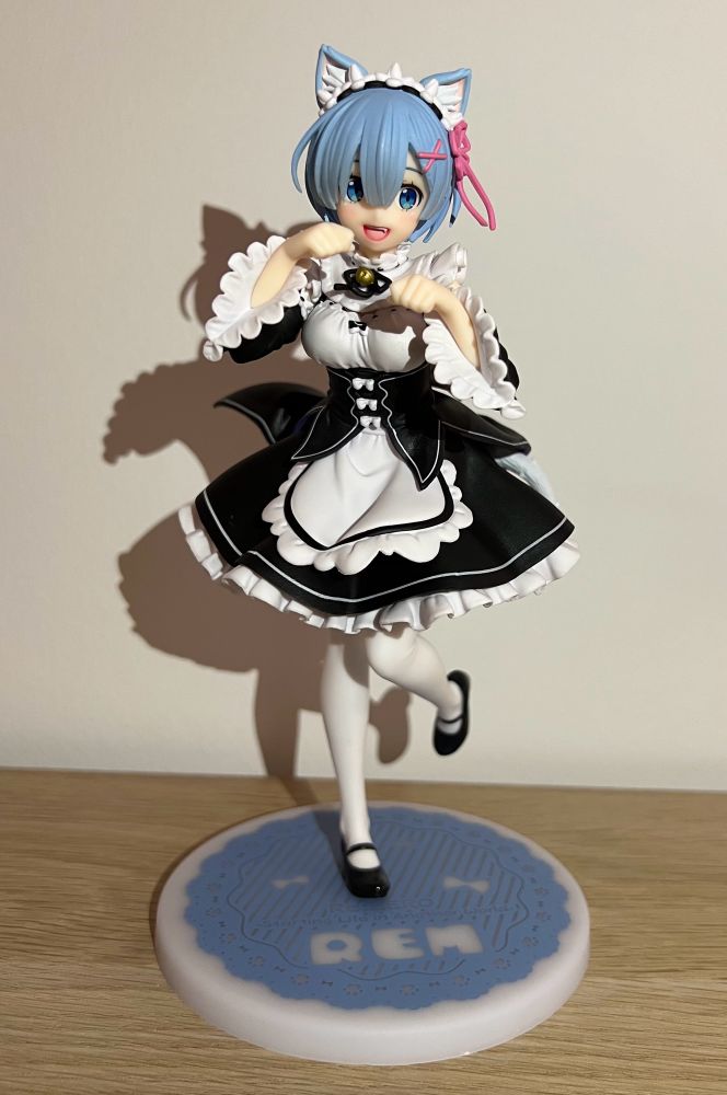 Picture of a figure. The figure is of the character Rem from the Re:Zero anime. The character is wearing a maid outfit and have cat ears. She’s having one foot up in the air behind her and her hands and folded in a cat pose in front of her.