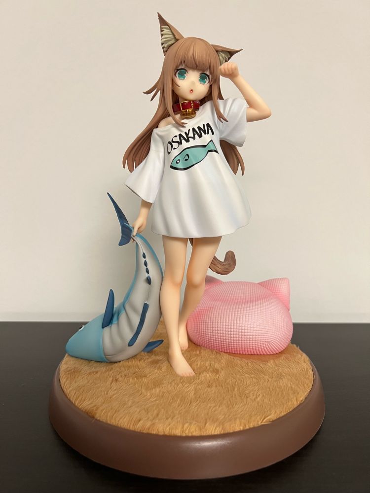 Figure of a catgirl standing on a base covered with a soft brown material.
She is holding a big fish shaped plush and have a pink bean bag with two cat ears beside her.

She is based on the illustrator 40hara's real life cat who've been turned into a catgirl with the same mindset of a cat.