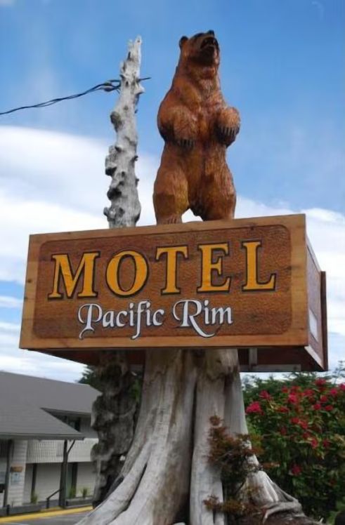 A Motel sign reading "Pacific Rim Motel" in Ucluelet with a wooden bear above it