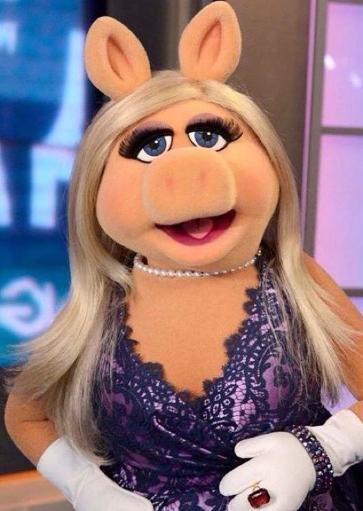 Miss Piggy wearing a purple dress that has a darker purple lace pattern over it. 