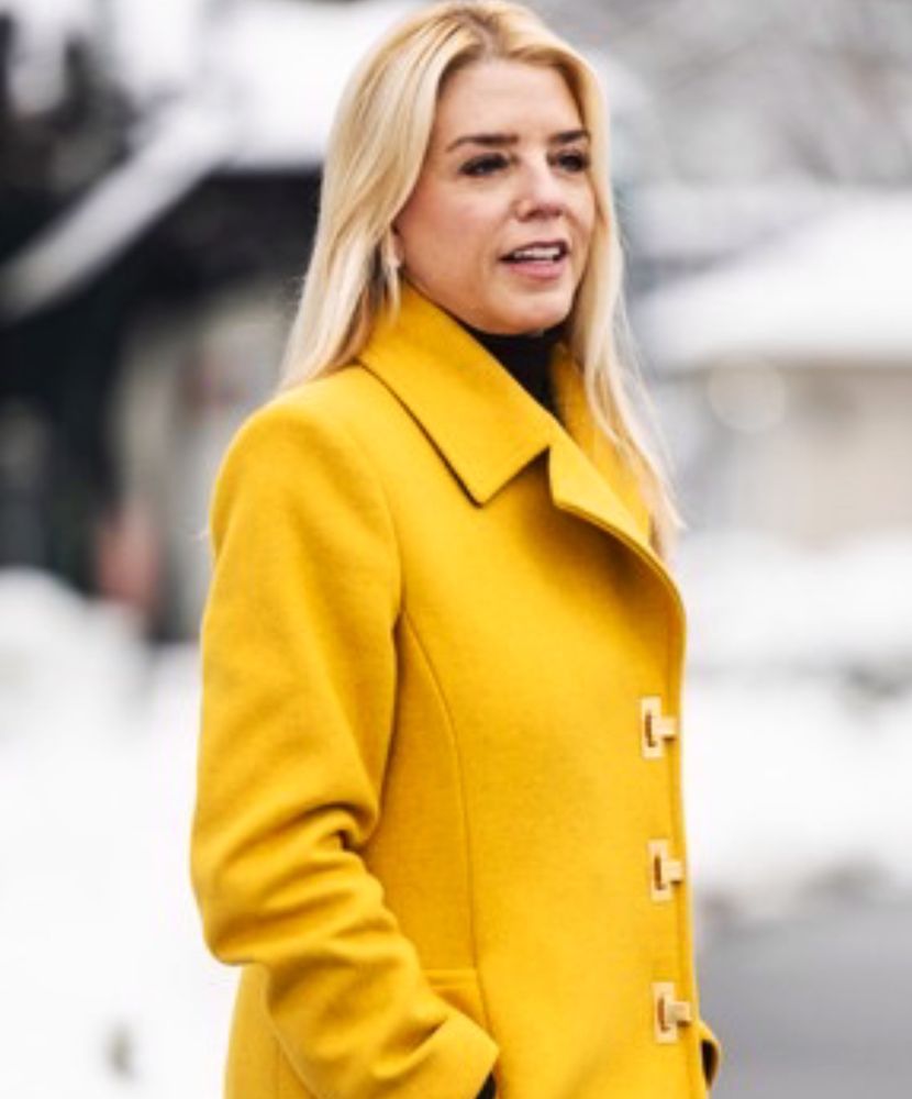 Pam bondi and he side profile wearing a dark yellow coat. 