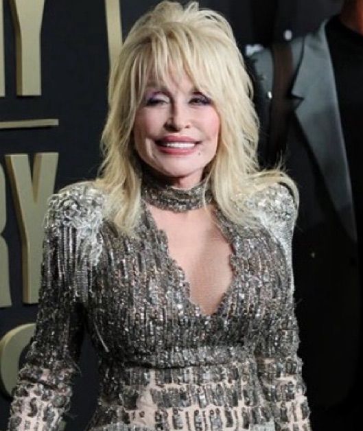 Dolly Parton dressed in silver beaded outfit.