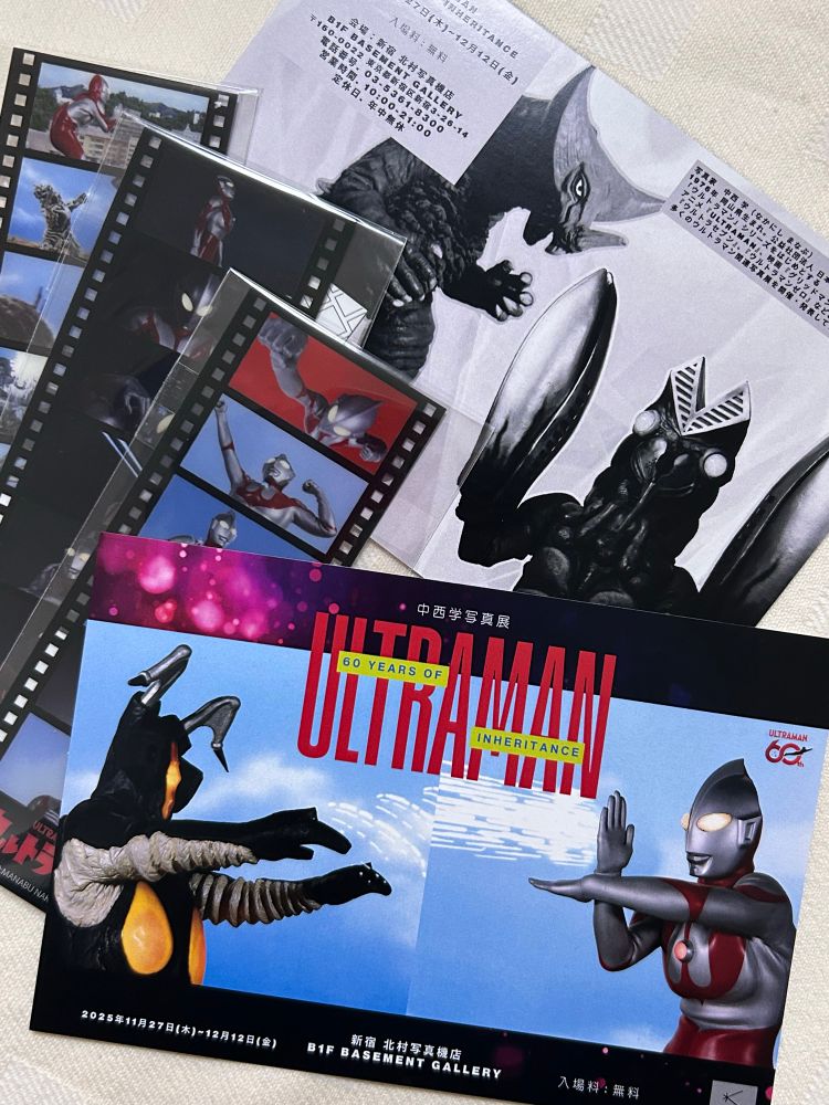 写真展の案内ハガキ。ウルトラマンとゼットンの写真が使われている。裏面はモノクロになったゴモラとバルタン星人が載っている。購入したグッズのポジフィルム風しおりと一緒に。