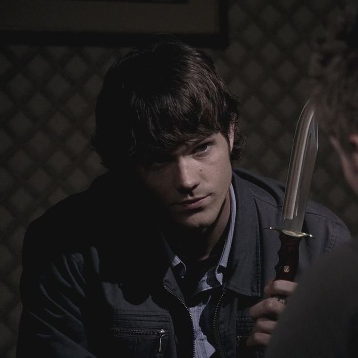 Sam Winchester (Jared Padalecki) in a dark room holds a glinting knife, tension evident as they face in supernatural 