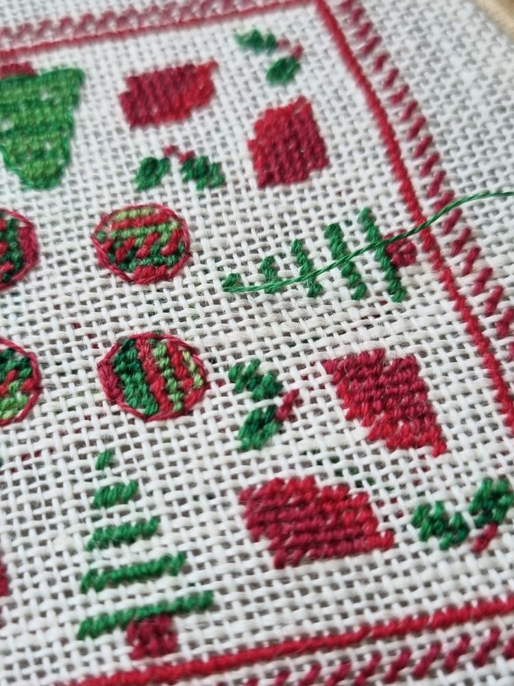 Close up of a christmas themed cross stitch WIP. The trees aren't finished