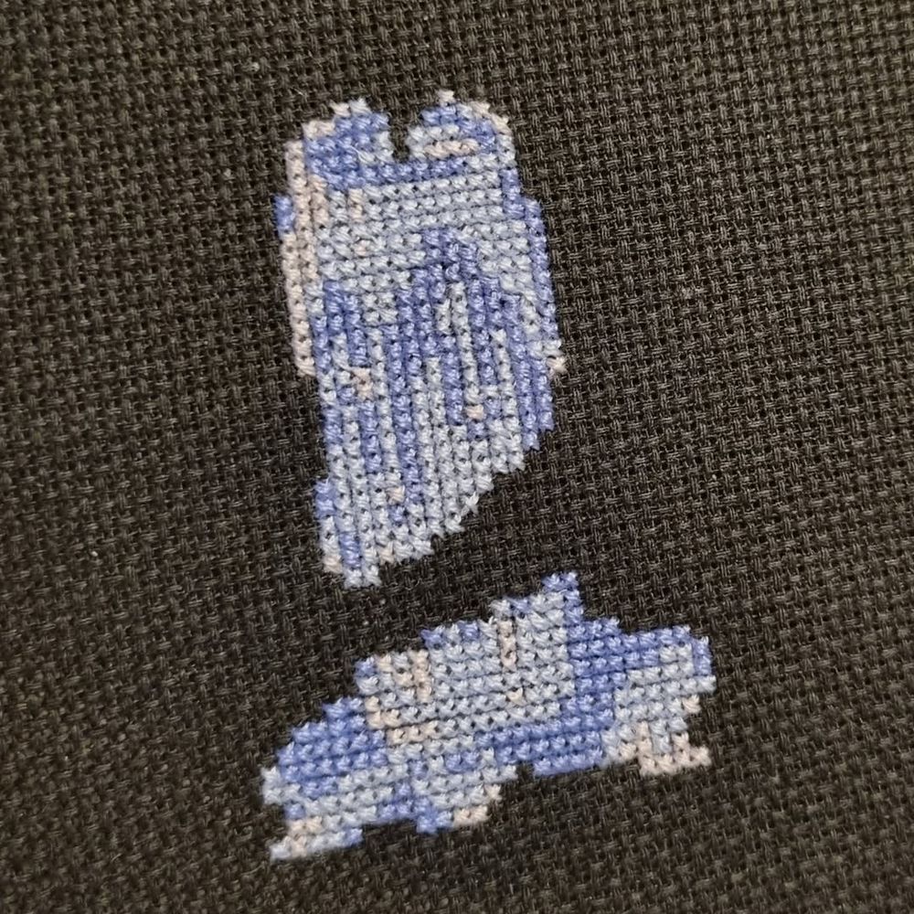 Cross stitch work in progress of a melting blue candle