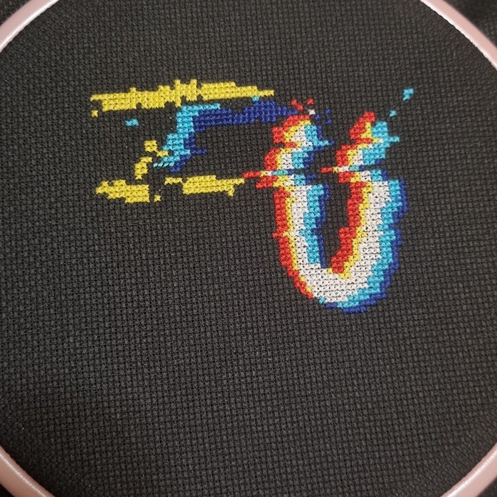 Glitchy cross stitch on black aida, starting to spell out "FU"