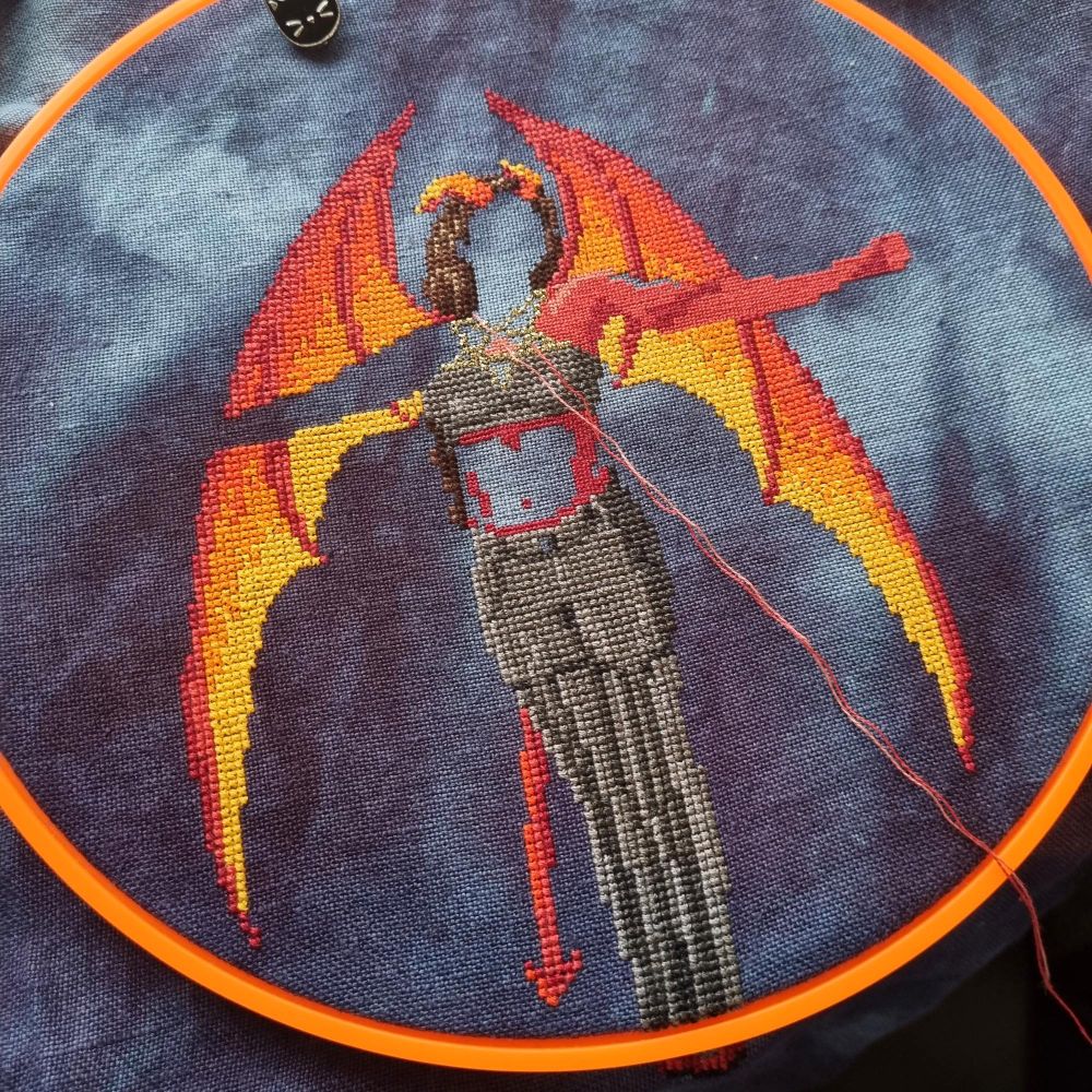 cross stitched demon woman with half finished red skin stitched one over one