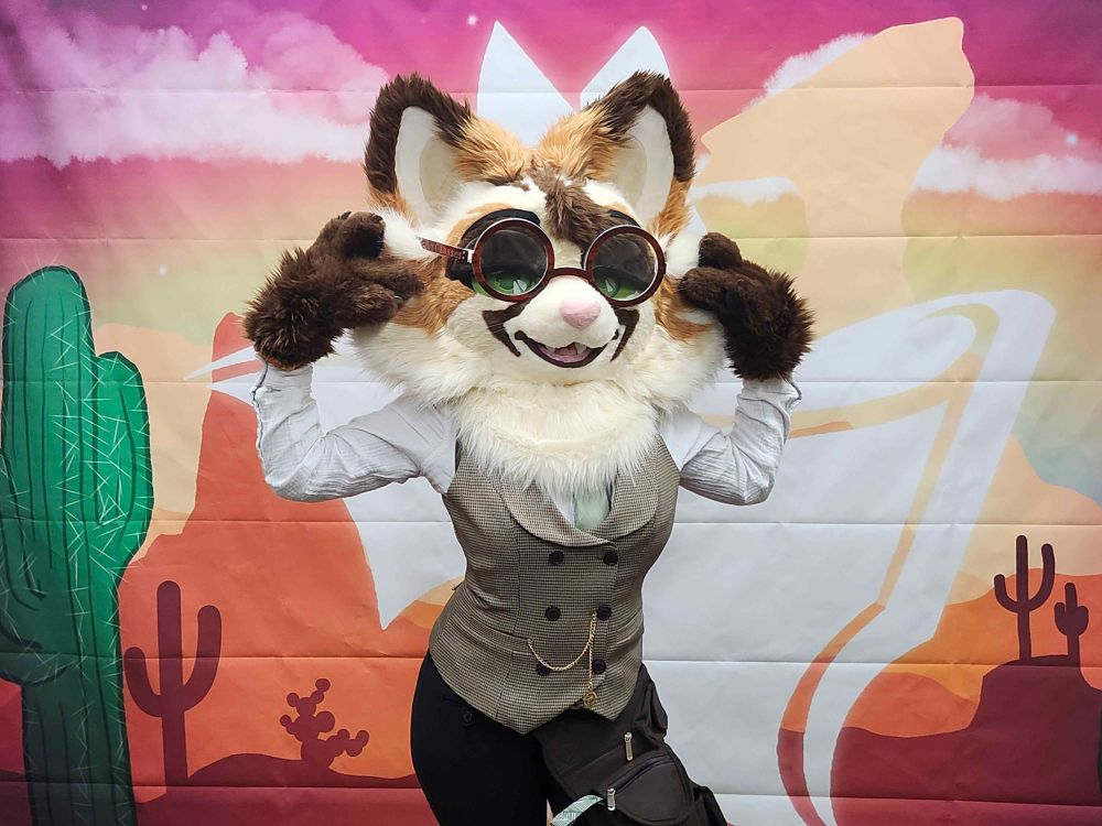 A white, tan and brown partial cat fursuiter with glasses