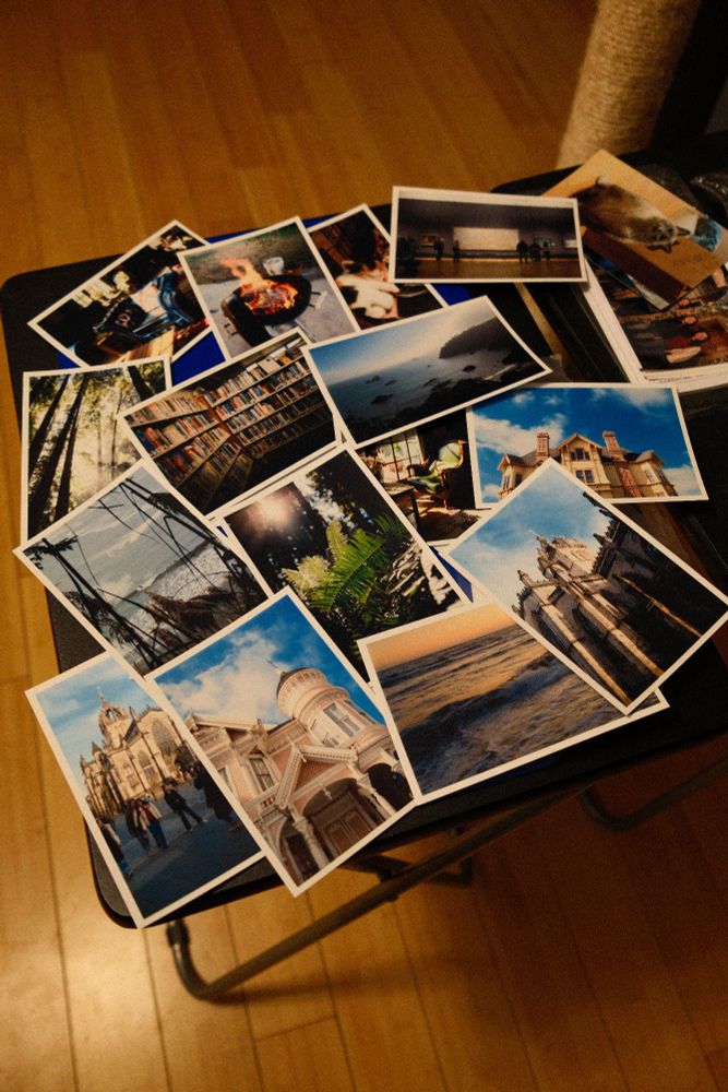 A small table is covered in 4x6 printed photos of various images.