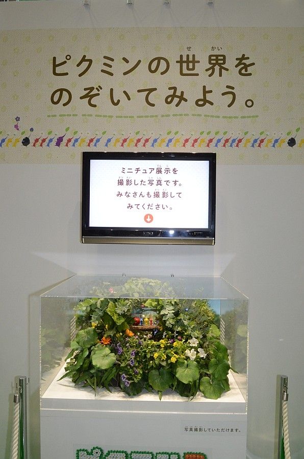 Japanese text on the wall at the Pikmin 3 booth at World Hobby Fair Summer 2013. According to Google Translate, it reads "Let's take a look at the world of World Pikmin. This is a photo of the miniature exhibit. Everyone please try taking pictures."
