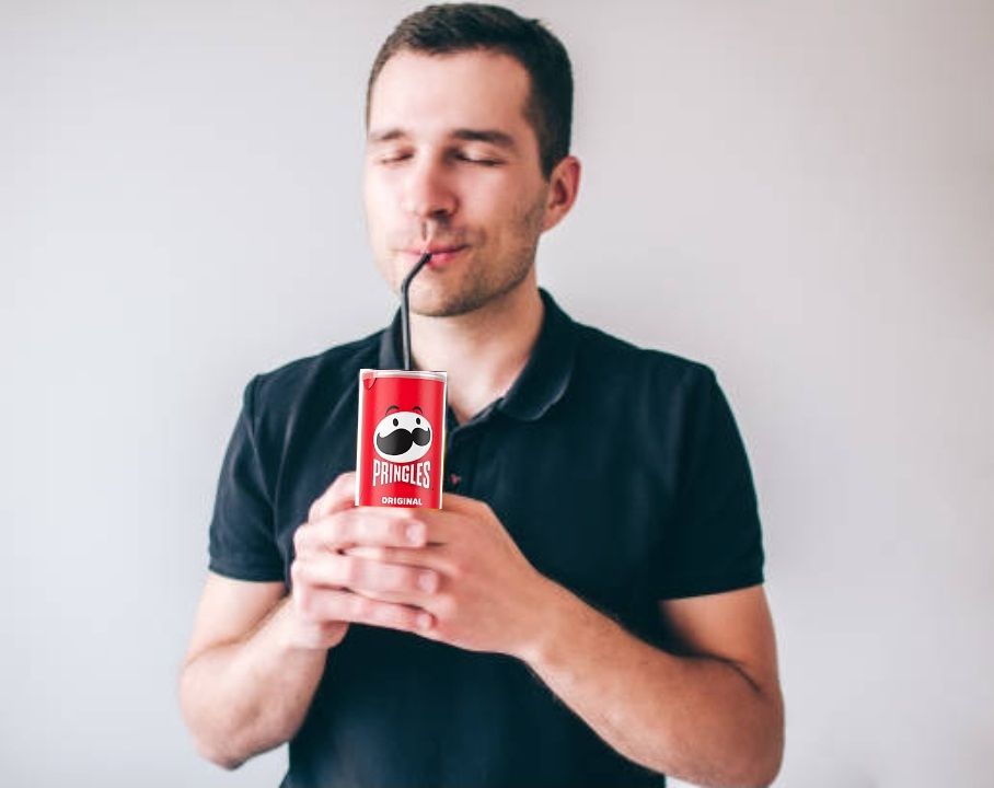 man holding a Pringles can with a straw in It and sipping from it