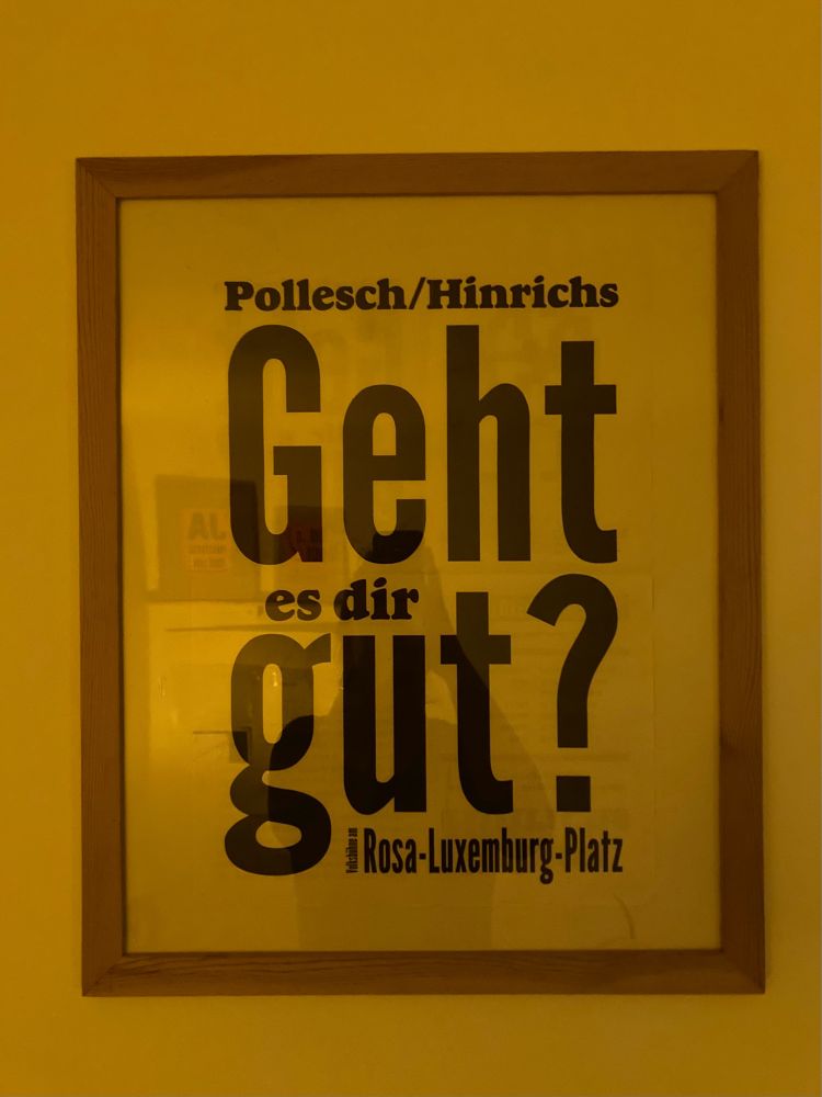 Weißes Poster von „Geht es dir gut?“ in einfachem Holzrahmen an einer Wand