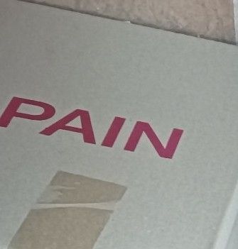 Recorte de la foto original donde sale una caja de cartón con el texto -pain (dolor) 