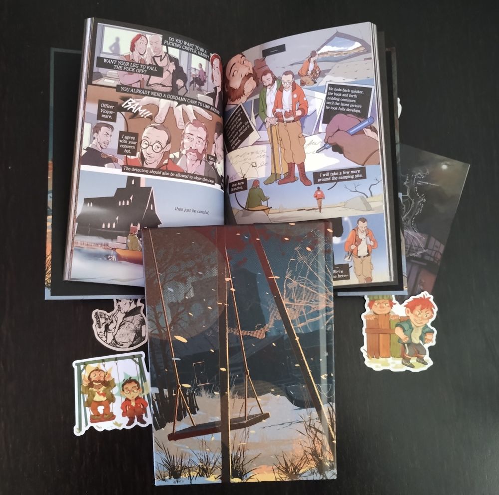 Foto del fanzine bocabajo rodeado de pegatinas, postales, blocs de notas con otro ejemplar abierto debajo