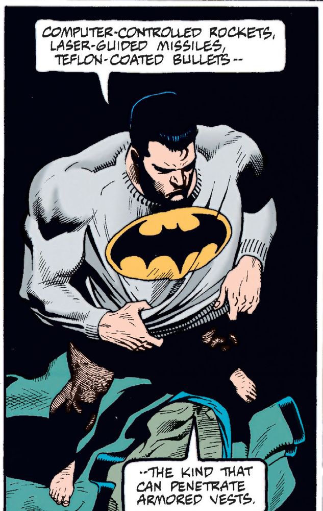 Bruce Wayne is donning the top half of the Batsuit - it is a grey long sleeved shirt, with a black Bat symbol within a yellow oval.  He is not wearing pants.