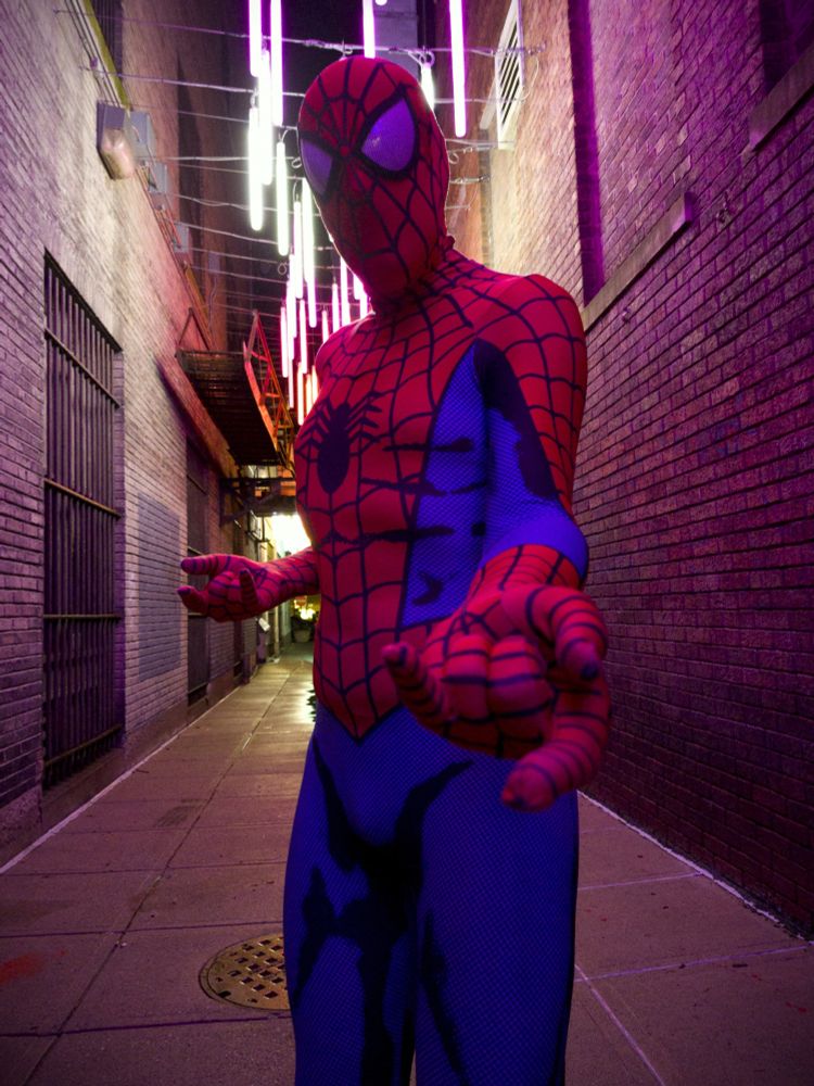 A man posing in a spandex Spider-Man suit. 