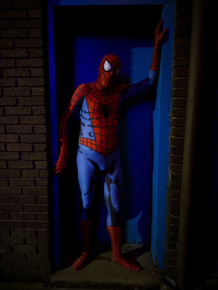 A man posing in a spandex Spider-Man suit. 