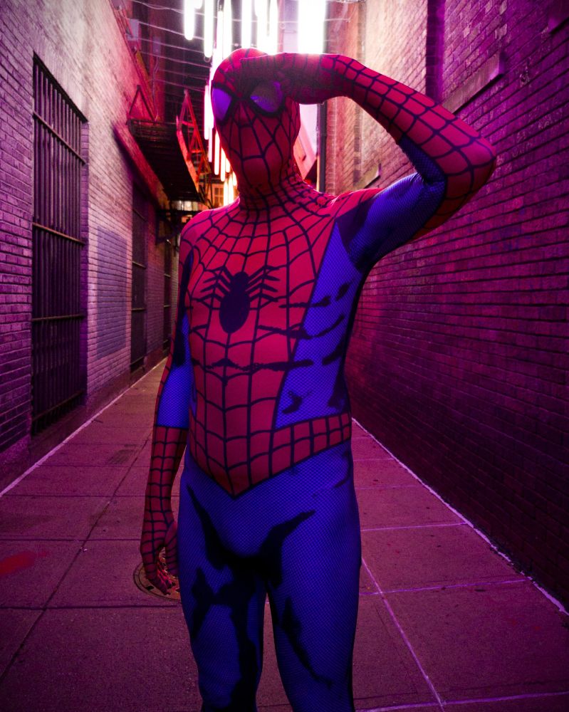 A man posing in a spandex Spider-Man suit.