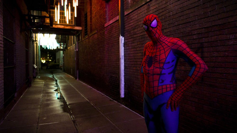 A man posing in a spandex Spider-Man suit.