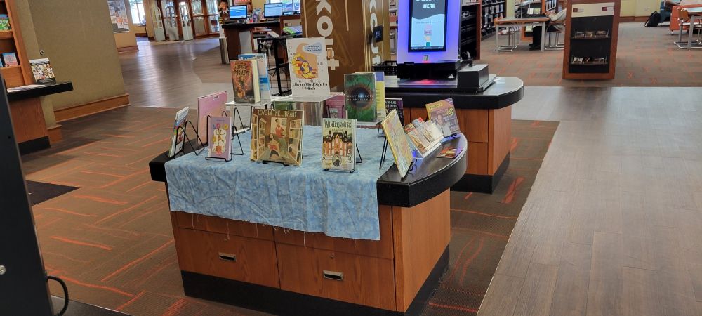 A display of young adult and children's books, all with thematic ties to libraries, reading, and the importance of literacy and access to literature.