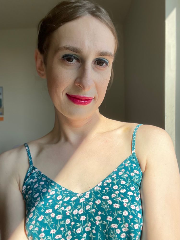 Luna selfie. It’s wearing a bright red lip gloss, eyeliner, blue eyeshadow, and a blue floral print sundress