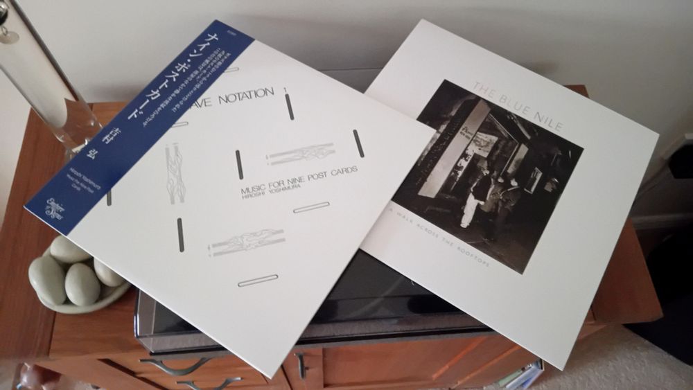 Album covers for 'Music For Nine Postcards' by Hiroshi Yoshimura, and 'A Walk Across The Rooftops' by The Blue Nile, lay on top of record player.