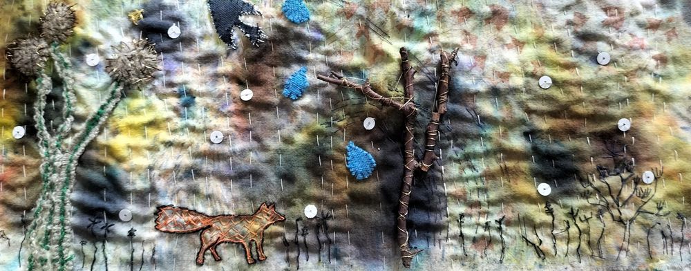 Textile panel on a wintry tgeme. Inky abstract background with stitched and printed elements on top-plants, birds, a fox. And a twig tree.