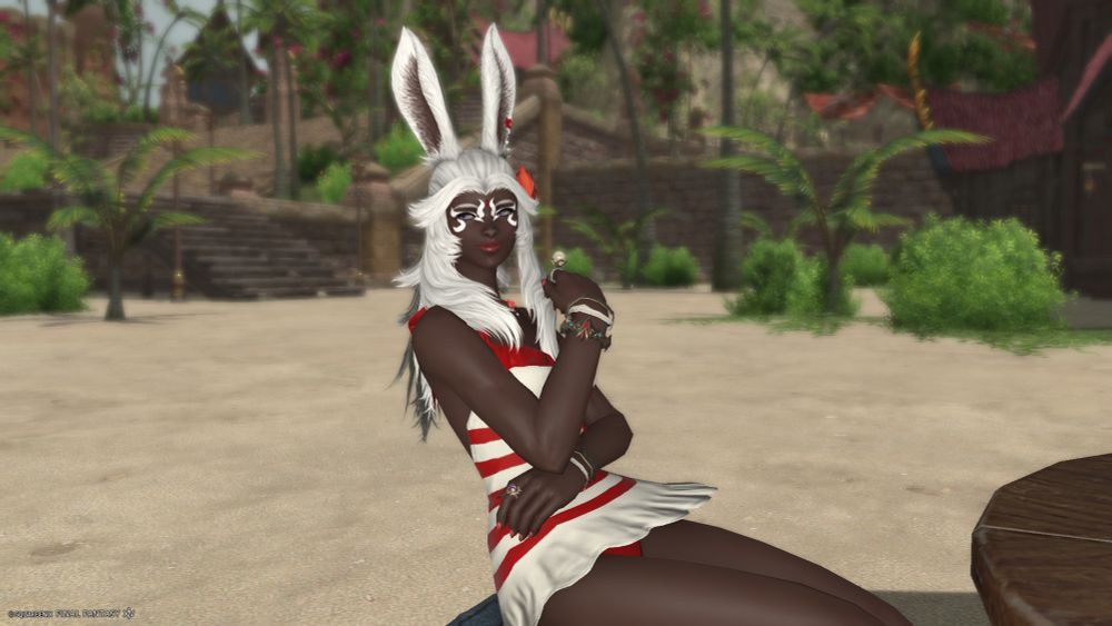 Oro sits at a table at the beach and gazes out at the water (daytime version)