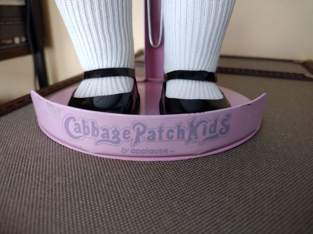 The base of a pink metal doll stand branded with "Cabbage Patch Kids" 