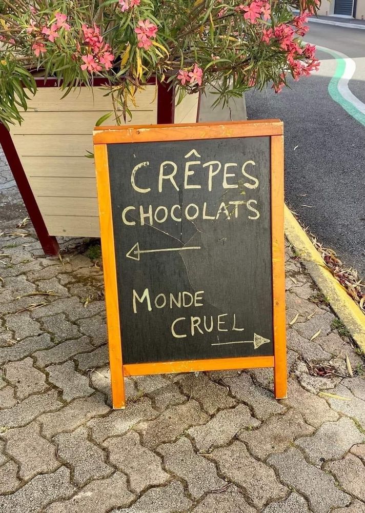 French sign saying (in French) "Crepes and chocolates", left arrow. "Cruel world", right arrow. Harvested from the webs, no idea of attribution.
