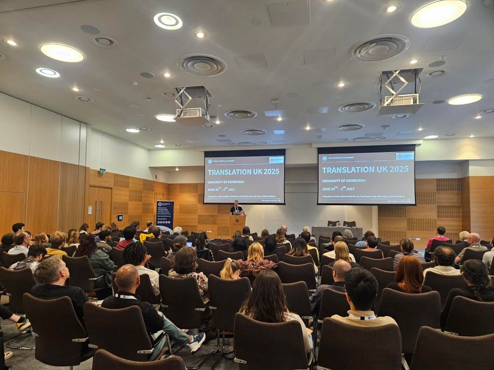 Audience seated in a conference room listening to a speaker presenting at the Translation UK 2025 event at University of Edinburgh.